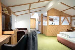 A cozy room with a desk, a chair, a bed, and a kitchenette. - Haus Katharina - Dorfblick (Kaprun)
