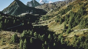 A mountainous landscape with a winding road, a ski lift, and a building with a view of the mountains. - Haus Katharina - Dorfblick (Kaprun)