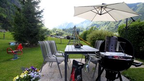 An outdoor patio with a grill, chairs, a table, and a potted plant. - Haus Katharina - Kitzsteinhornblick (Kaprun)