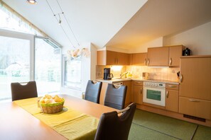 Eine moderne Küche mit Holzschränken, einem Esstisch mit Stühlen und einem Korb mit Brot.