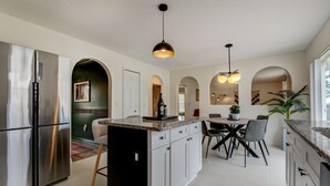 Een moderne keuken met roestvrijstalen apparatuur, een centraal eiland met zitplaatsen en hanglampen.