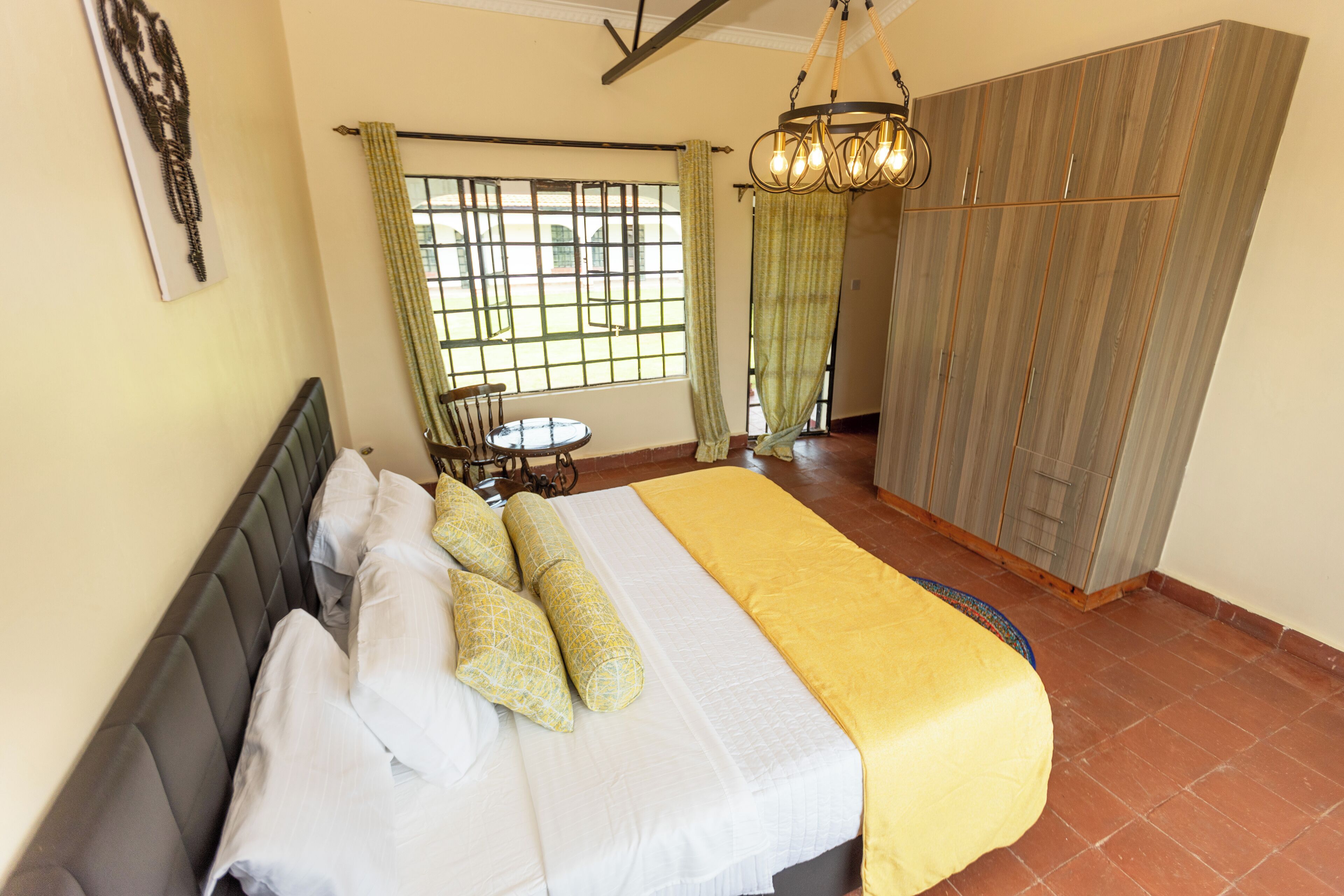 Un dormitorio con cama, una silla, un armario y una ventana con cortinas.