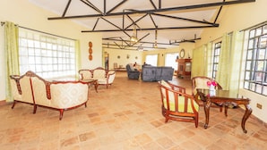 A spacious living room with a high ceiling, large windows, and a fireplace. - Ene Hacienda (Maili Tisa)