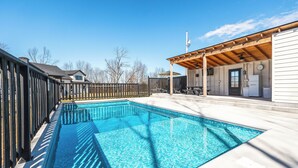 Piscina con terraza de madera y zona de patio cubierta.