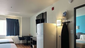 A hotel room with two beds, a refrigerator, a desk with a chair, a mirror, and a window with curtains. - Studio 6 – Las Cruces, NM - Telshor (Las Cruces)
