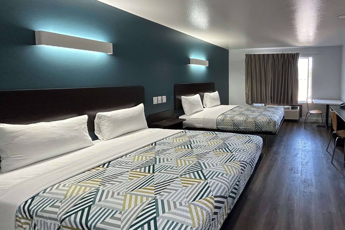 A hotel room with two beds, a desk, and a chair.