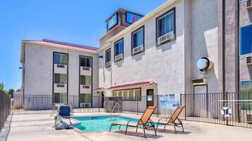 A building with a swimming pool, outdoor seating, and a lifebuoy.