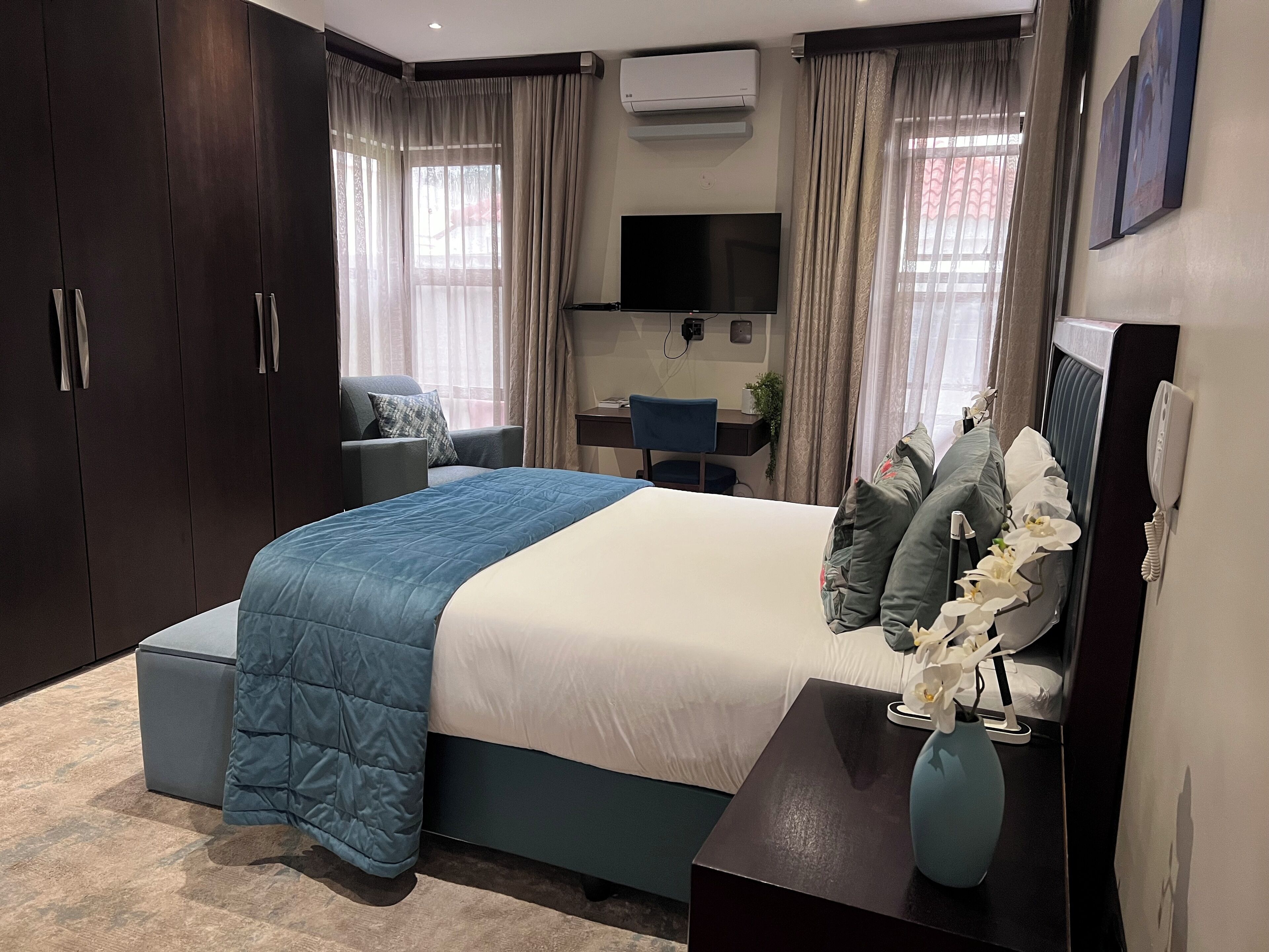 Un dormitorio moderno con una cama grande, un escritorio y un televisor.