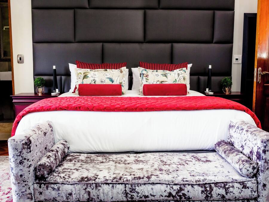 Un dormitorio con una cama grande, cabecera, mesitas de noche y un sillón con estampado.