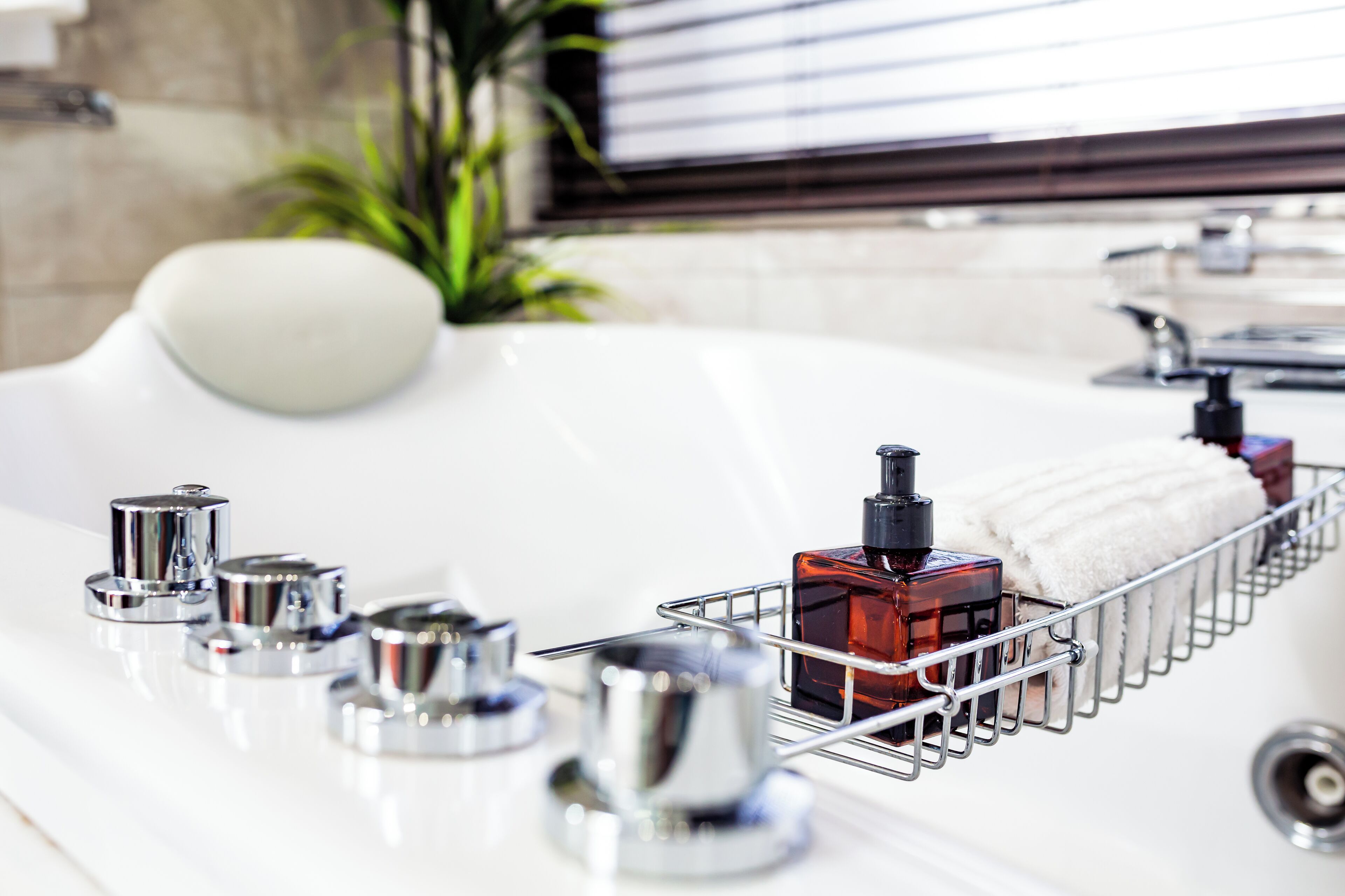 A bathroom with a bathtub, a metal rack holding toiletries, and a potted plant.