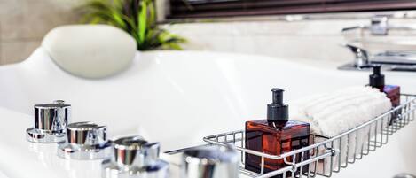 A bathroom with a bathtub, a metal rack holding toiletries, and a potted plant.