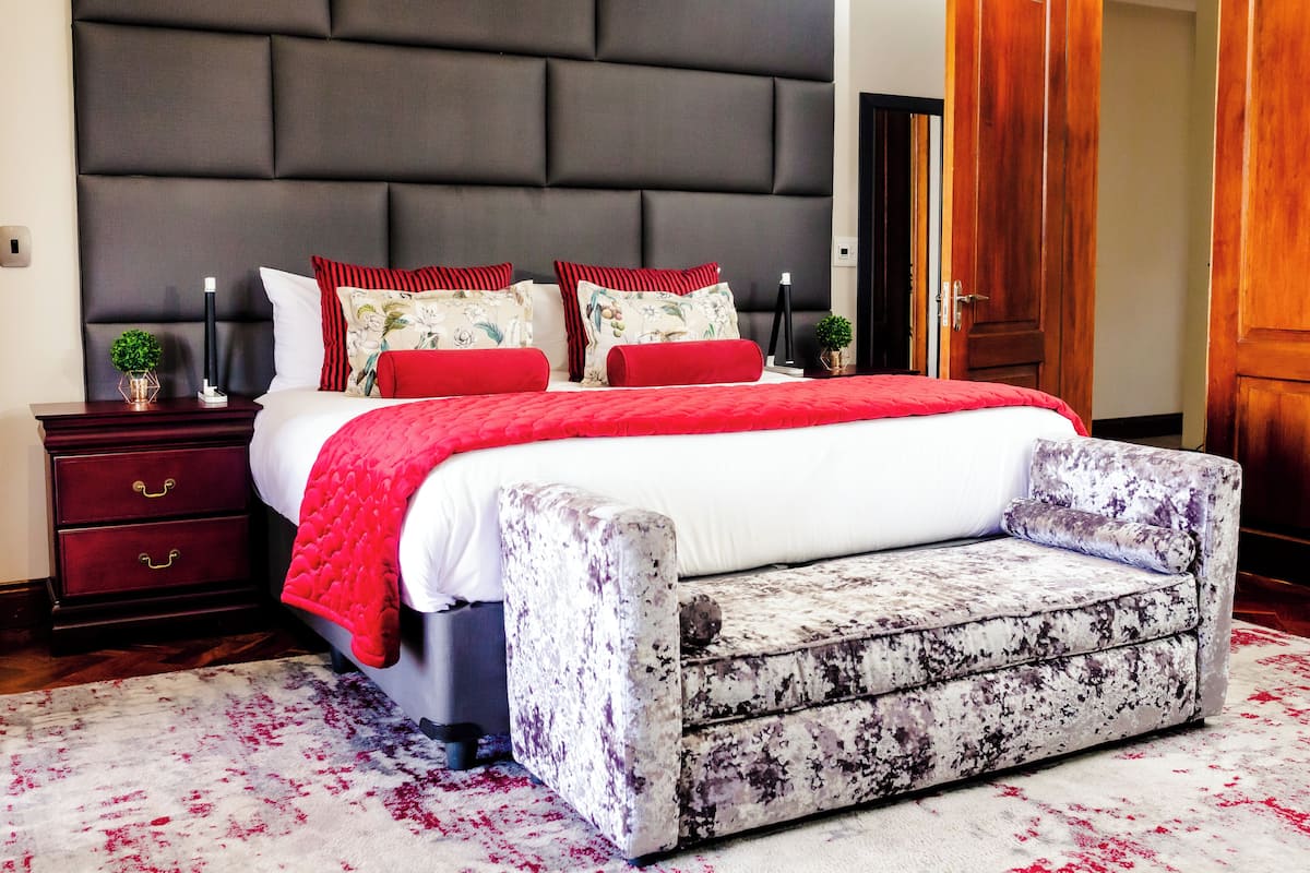 A bedroom with a large bed, a nightstand, a bedside table, and a wooden door.