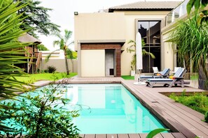 Una piscina al aire libre, sombrillas, tumbonas