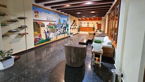 Un hall d’entrée orné d’une fresque murale, un comptoir d’accueil, un espace détente et un escalier agrémenté d’étagères à livres.