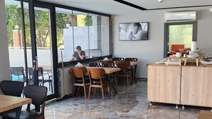 Un comedor moderno con suelo de mármol, muebles de madera y ventanas amplias con vistas al exterior.