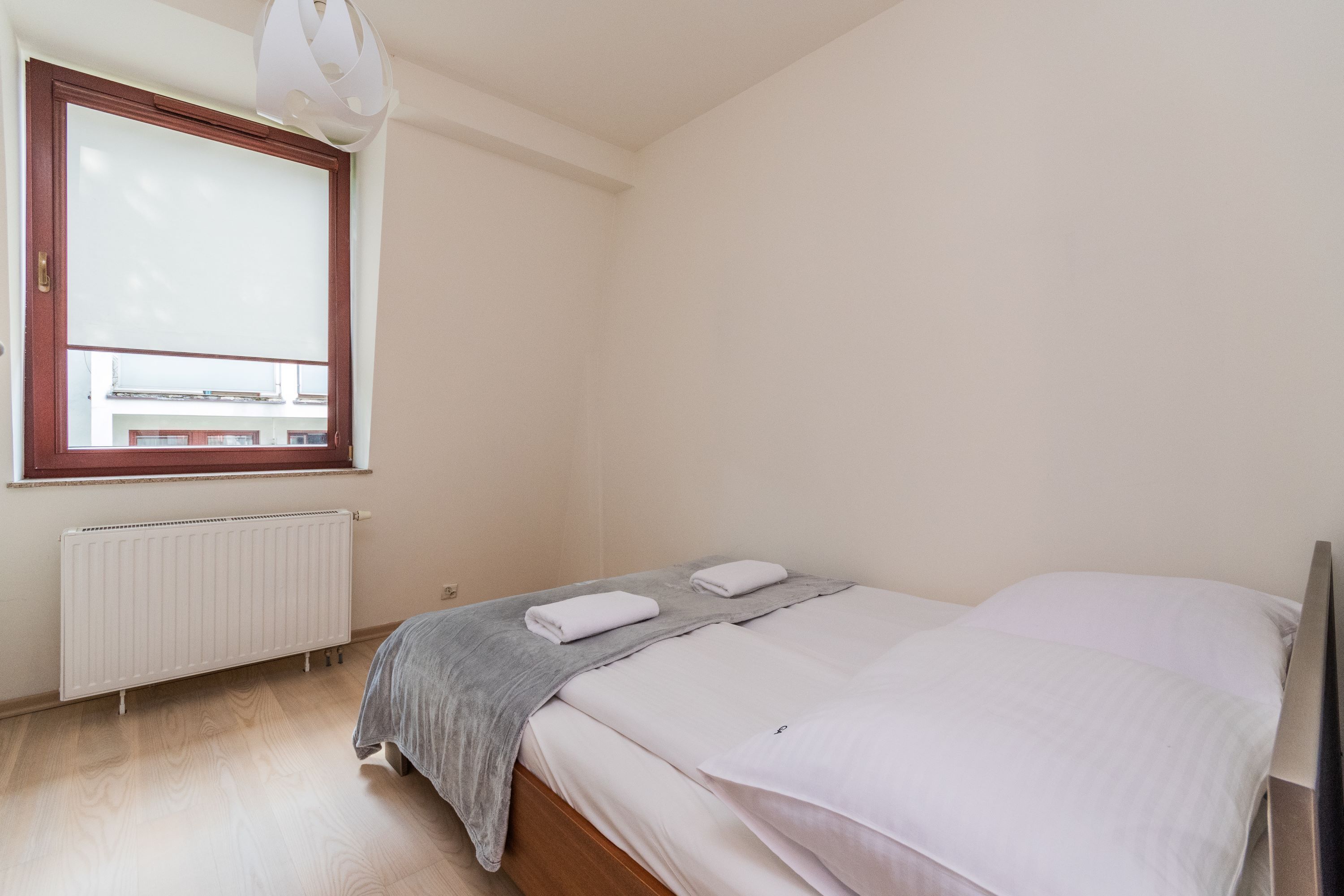 Une chambre à coucher avec un lit, une fenêtre, un radiateur et un luminaire au plafond.