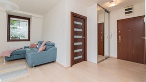 Ein modernes Wohnzimmer mit einem Ecksofa, einer Holztür und einem großen Spiegel.
