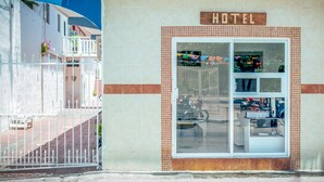 Fachada de un hotel con entrada de azulejos, un letrero que indica que es un hotel y una ventana que muestra diversos artículos.
