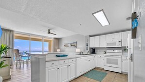 A modern kitchen with white cabinets, a central island, and a view to the outside.