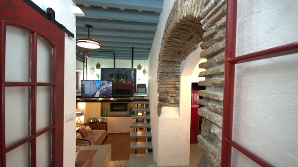 A cozy interior with a stone archway, a staircase, and a living area with a television. - 340 Livingtarifa Warhol (Tarifa)