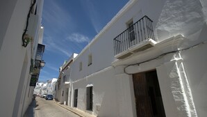 A narrow, cobblestone street lined with white buildings featuring balconies and wooden doors. - 340 Livingtarifa Warhol (Tarifa)