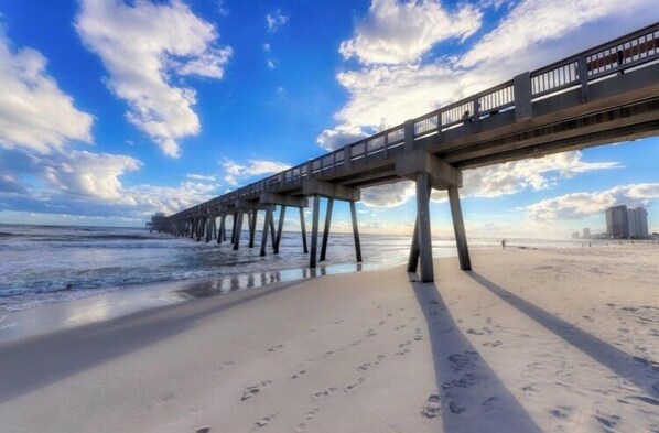 Ein Strand mit einer langen Seebrücke, die sich ins Meer erstreckt.