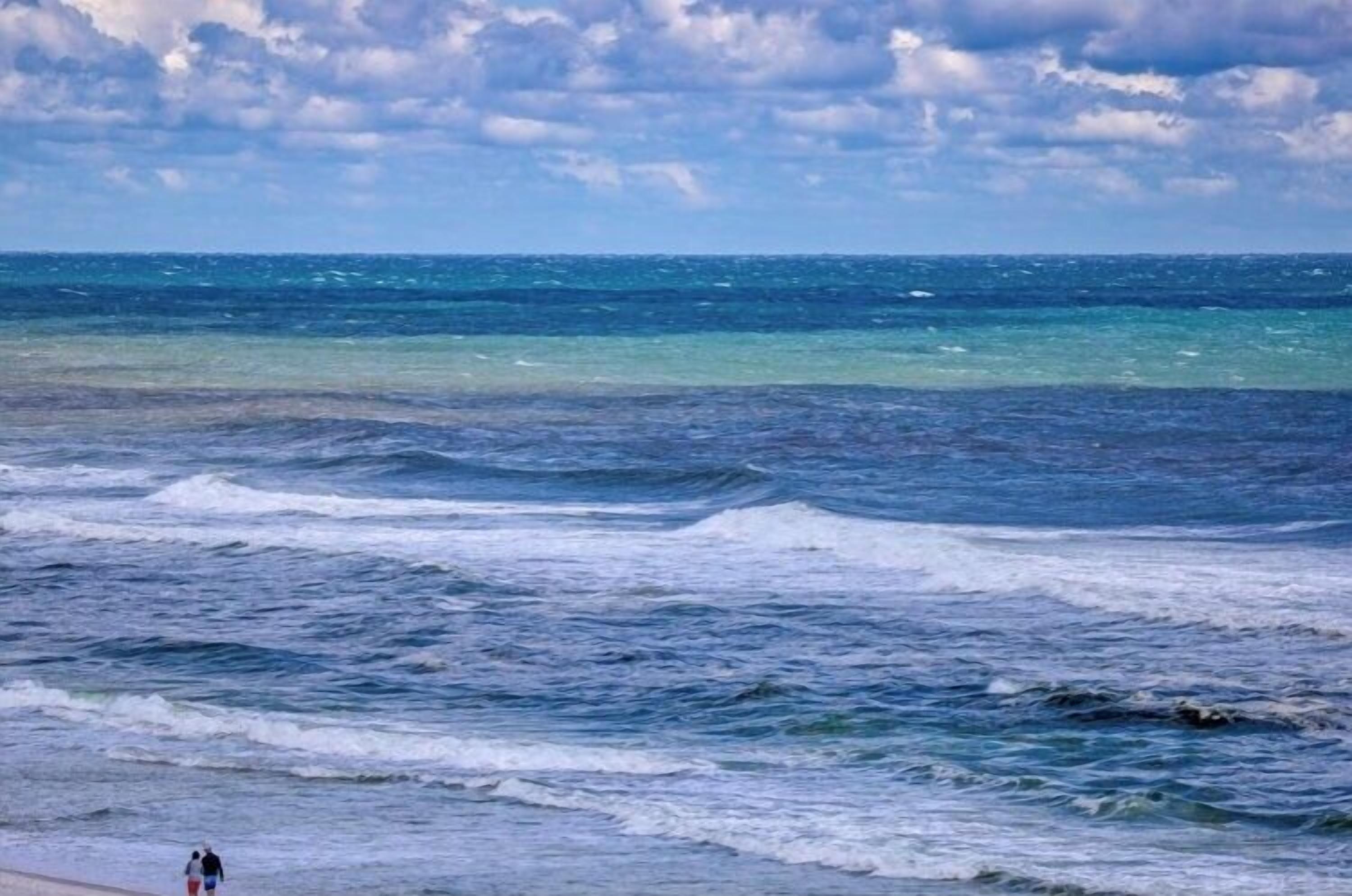 Una playa con olas y un cielo nublado.