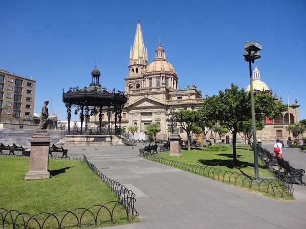 A plaza with a central monument, a building with a dome, and a statue. - New Apt in GDL Near Cathedral  (Guadalajara)