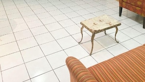 A living room with a television on a wooden stand, a sofa, a patterned armchair, and a tiled floor. - New Apt in GDL Near Cathedral  (Guadalajara)