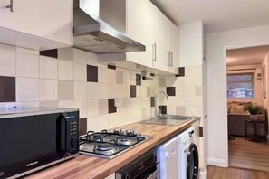 Una cocina moderna con estufa a gas, microondas y lavavajillas.