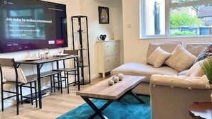 A living room with a TV, a sofa, a coffee table, and a dining area. - Cozy home with a garden walkable distance to the heart of Hertford   (Hertford)