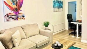 A living room with a beige sofa, a coffee table, and a painting on the wall.