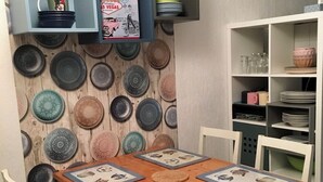 A dining area with a wooden table, white chairs, and a wall decorated with various plates. - Studio at the foot of the slopes/Mountaineering/Hiking accrobranche La Bresse (La Bresse)
