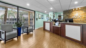 A reception area with a stone wall, a reception desk, and two grey chairs. - Partial Bay Views & Pool 1BR (Tampa)