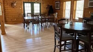 A spacious dining area with wooden floors and a large round table surrounded by chairs.