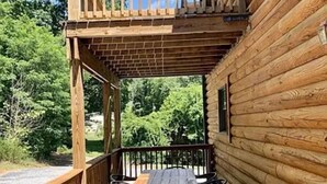 A wooden deck with a table and chairs, surrounded by a wooden fence, overlooking a forested area.