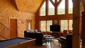 A wooden interior with a pool table, a sofa, and a television.