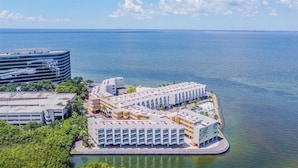 An aerial view of a waterfront hotel with multiple buildings, a marina, and a large body of water. - Family-Friendly 1BR w/ Pool Bar & Restaurant (Tampa)
