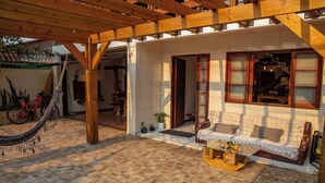 A covered patio area with a wooden pergola, a hammock, and a sofa with cushions. - Nomades beach - Adventure Hostels (Florianópolis)