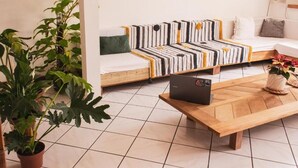 A modern living room with a sofa, a coffee table, and potted plants. - Nomades beach - Adventure Hostels (Florianópolis)