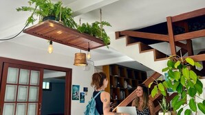 A spacious living area with a staircase, a wooden table, and a hanging plant. - Nomades beach - Adventure Hostels (Florianópolis)