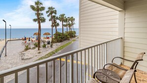 Un balcon avec vue sur la plage, les palmiers et un ciel dégagé.