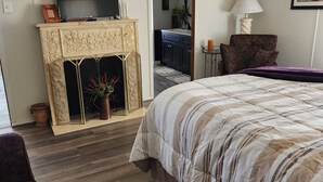A bedroom with a bed, a fireplace, a television, and a ceiling fan. - Welcome to our charming farmhouse retreat nestled in the Kentucky countryside. (Corinth)