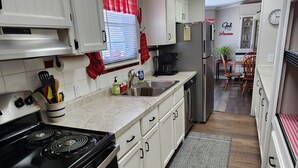 A compact kitchen with white cabinets, a black stove, and a red towel. - Welcome to our charming farmhouse retreat nestled in the Kentucky countryside. (Corinth)