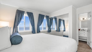 A spacious bedroom with a large bed, a walk-in closet, and a bathroom with a mirror and vanity.