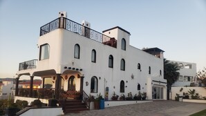 A two-story building with a white facade, multiple arched windows, and a balcony with black railings.