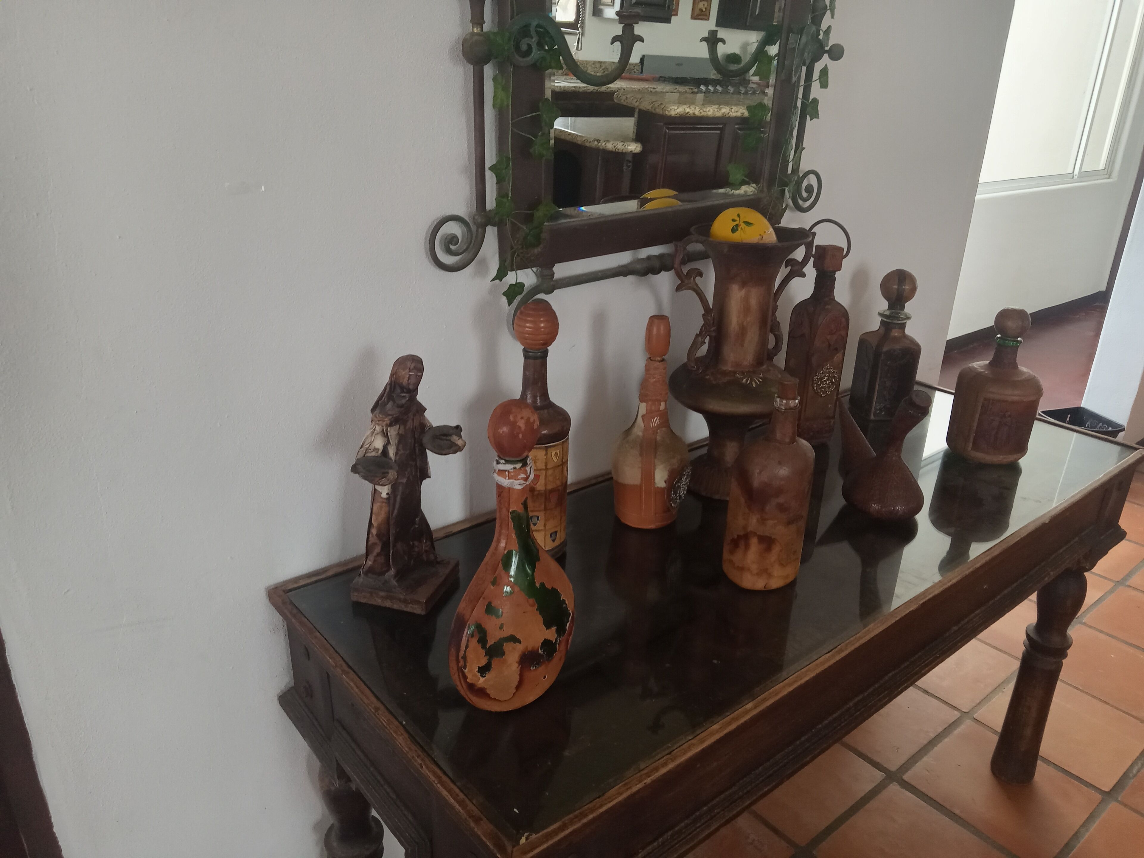 Uma mesa de madeira com vários frascos antigos e uma pequena estátua.