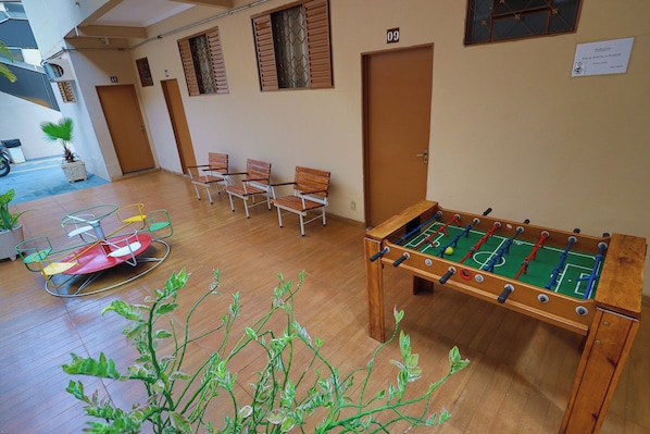 A room with a foosball table, several chairs, and a small table with a ball. - Hotel Portela II (Olímpia)