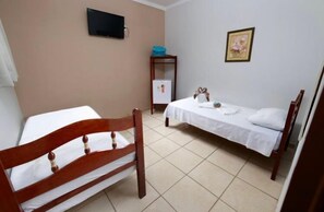 A room with two beds, a TV mounted on the wall, a small table with a blue cloth, and a framed picture on the wall. - Hotel Portela II (Olímpia)