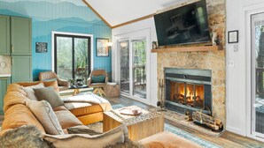 A living room with a stone fireplace, a large flat-screen TV, and a cozy seating area. - Blue Ridge Bliss 9BR/6BA: 2 Homes Across the Street from each other! Sleeps 24 (Wintergreen Resort)